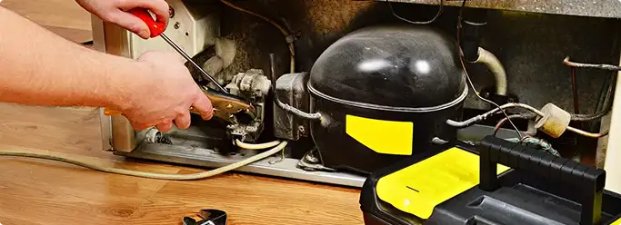 Refrigerator repair technician fixing the compressor and wiring in Smyrna, GA