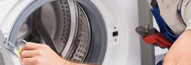 Appliance technician repairing a clothes dryer drum and internal parts in Marietta, GA