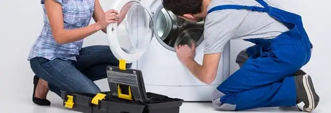 Washer repair technician inspecting a front-load washing machine with tools in Marietta, GA