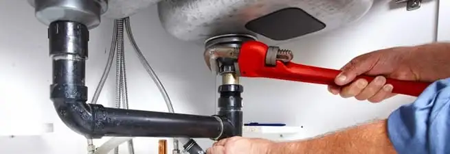 Garbage disposal repair technician tightening the sink drain and disposal connection in Marietta, GA