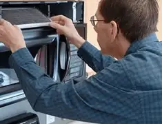 Appliance repair technician replacing a microwave vent filter in Marietta, GA