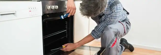 Oven repair technician inspecting and servicing an electric oven in Marietta, GA