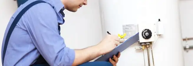 Water heater repair technician inspecting the unit and recording service notes in Marietta, GA