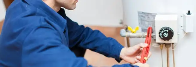 Water heater repair technician adjusting the temperature control and gas valve in Marietta, GA